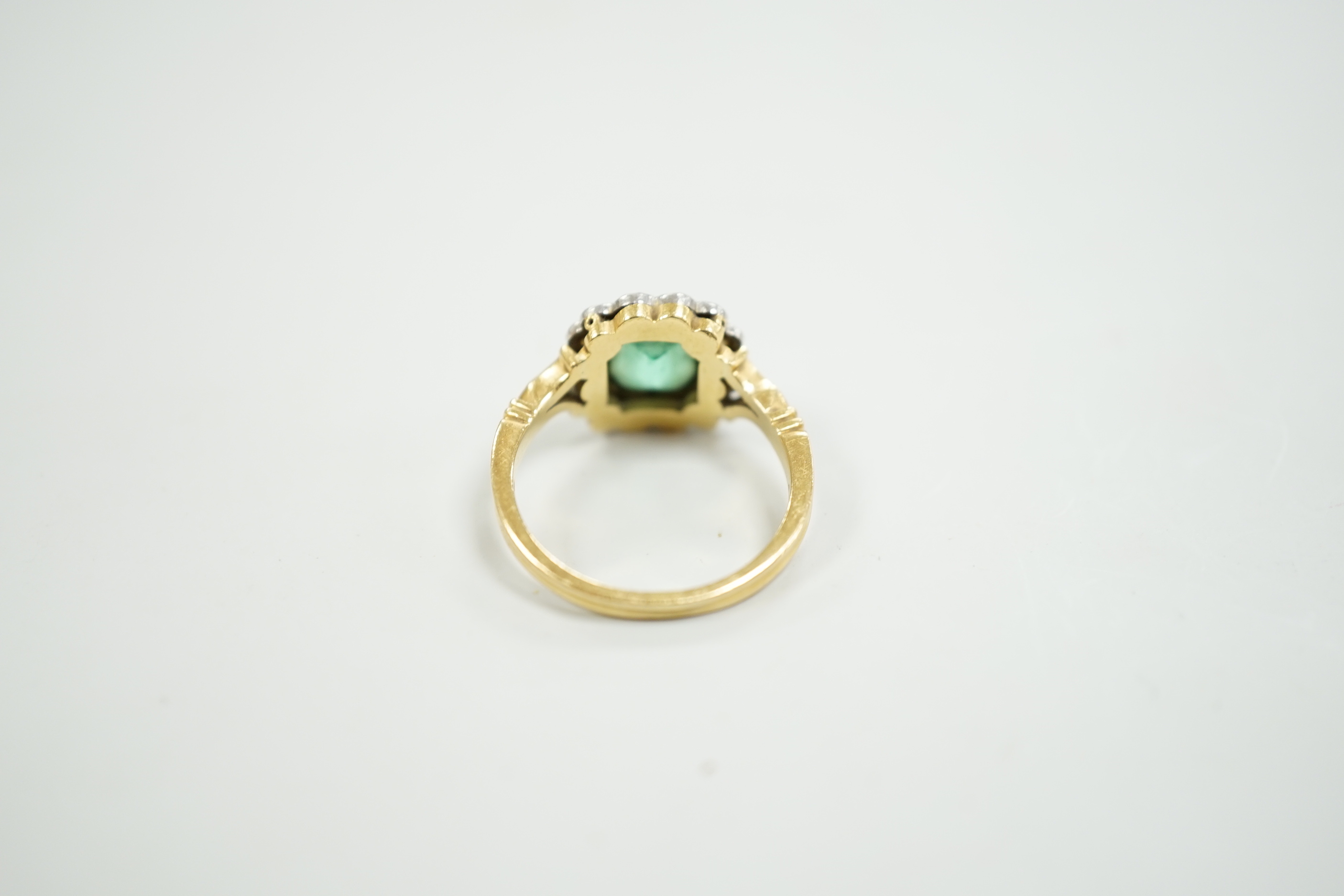 A modern 18ct gold, emerald and diamond set circular cluster ring, size O, gross weight 5 grams.